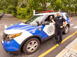 two people in Public Safety uniforms in or alongside a R I S D Public Safety vehicle